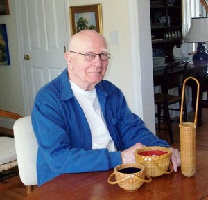 Paul Willer, basket maker, at the table with some of his baskets